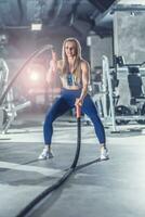 Sporty woman exercising with battle ropes at the fitness gym photo