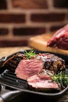 Grilled beef steak in grill pan with herbs rosemary on wooden table photo