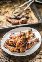 Grilled hicken legs BBQ with spices herbs and sesame on baked paper. Roasted poultry meal on white plate photo