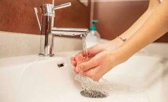 Washing hands with water and liquid soap in the bathroom photo