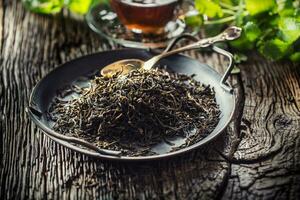 seco té hojas en cuenco en rústico de madera mesa foto