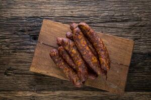 Sausages. Smoked Sausages. Chorizo sausages with vegetable rosemary spices and kitchen utensil. photo