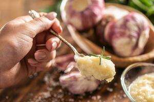 Detail of a teaspoon of garlic paste with fresh garlic in the background photo