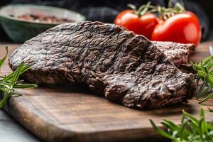 Two beef rump steaks with herbs tomatoes salt and spices on butcher board photo