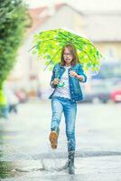 Portrait of beautiful young pre-teen girl with umbrella under rain photo