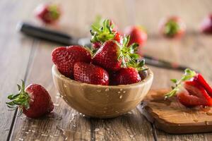 Juicy washed strawberries in wooden bowl on kitchen table photo