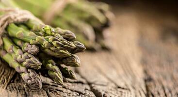 Bunch of fresh asparagus on rustic oak table photo