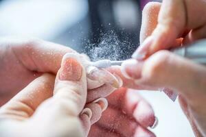 Repairing old gel nails with a nail grinder in nail studio - salon. Nails manicure. photo