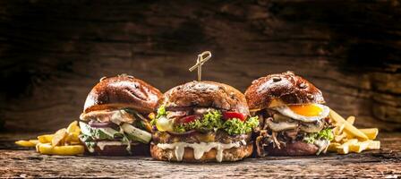 Front view on three large, beef salmon and kebab burgers stuffed with fresh vegetable salad and dressing photo