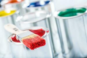 Close-up brush with red color lying on paint can. photo