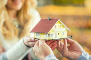 Young loving couple holding small model house photo