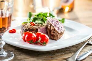 Beef Steak. Juicy beef steak. Gourmet steak with vegetables and glass of rose wine on wooden table photo