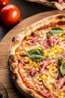 Italian pizza cardinale with ham prosciutto tomatoes corn and basil photo