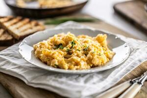 Tasty looking fresh hot scrambled eggs served in a plate with a sprinkle of fresh chives on top photo