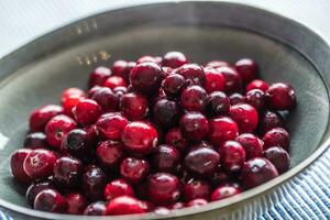 Fresh ripe cranberries in bowl on table close-up photo