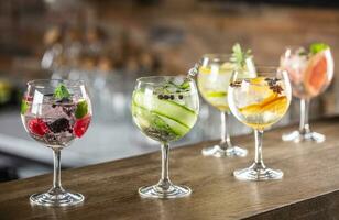 Gin tonic long drink as a classic cocktail in various forms with garnish in individual glasses such as orange, lemon, grapefruit, cucumber or berries photo