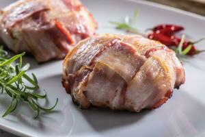 Crispy bacon wraps served on a plate with rosemary and chillies photo