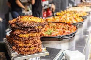 Fried potato pancakes and various stews in pans on offer during a fair or a street food event photo