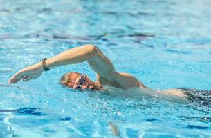 un masculino nadador nada gatear en un nadando piscina durante formación para un triatlón foto