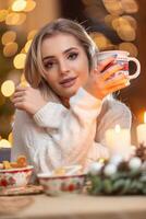 joven hermosa mujer en un Navidad atmósfera participación un taza con café o té foto