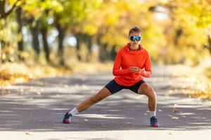 joven hembra atleta en ropa de deporte es calentamiento arriba antes de corriendo en el otoño parque foto