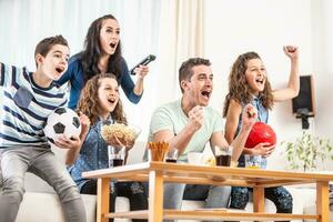 Raving fans cheering sports, as family of five watch football, match on the TV at home, screaming from joy photo