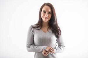 sonriente morena en un aislado blanco fondo, vestido en gris pull-over, mira dentro el cámara, sonriente foto