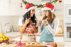 Daughter and mother make Christmas cookies from Linz. Mom tastes sweet jam and daughter spreads marmelade on a cookie. photo