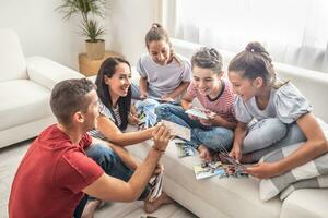 Father and mother show printed photos to their children sitting on a sofa at home