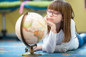 aburrido preadolescente niña vistiendo lentes mirando a un globo acostado en el piso foto