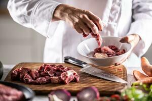 Chef puts pieces of pork into a bowl to cook it photo