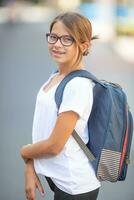 Young teenage in glasses and braces girl wears rucksack and a white t-shirt photo