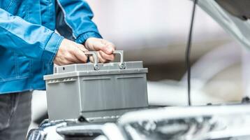 Mechanic replaces car battery in the car in the garage workshop photo