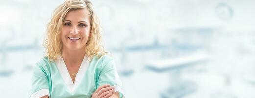 Blonde female doctor smiling into the camera, arms crossed on her chest, dressed in light green uniform with a blurred laboratory background, in a banner format photo