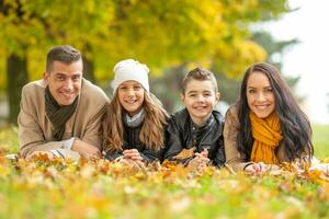 contento familia acostado en un cobija al aire libre en un hermosa otoño día foto