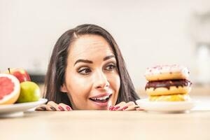 Girl preferring plateful of donuts instead of a plate with fresh fruit photo