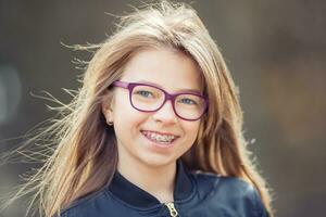 Portrait of a happy smiling teenage girl with dental braces and glasses photo