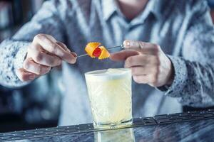 profesional barman haciendo cóctel bebida y decorado con frutas foto