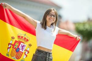 contento niña turista caminando en el calle con Español bandera foto