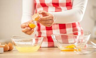 Detail of woman's hands separating egg yolks from the whites into two glass bowls photo