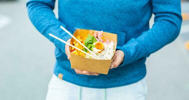 Young mans hands holding lunch in a box of recycled paper photo