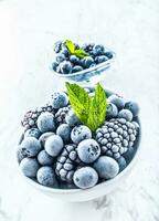 Close-up frozen blueberries and blackberries with mint leaves photo