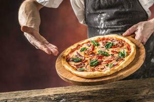 cocinero y Pizza. cocinero ofrecimiento Pizza en hotel o restaurante foto