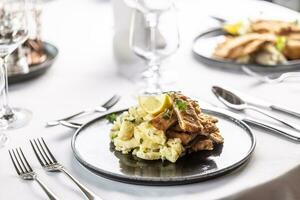 Wiener schnitzel cut into pieces and served on top of a potato salad pile photo