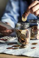 Putting 50 cents into a jar of euro coins by a woman counting bills photo