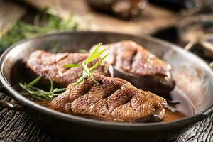 Three crispy duck breasts baked in an old rustic pan photo