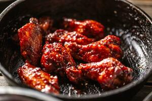 Spicy glazed marinated chicken wings in a dark pan photo