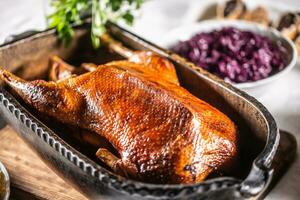 Crispy baked goose in an original baking dish on the festive table photo