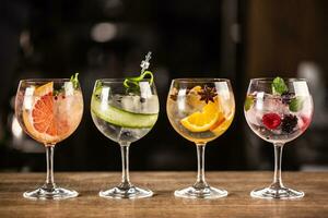 Gin tonic long drink as a classic cocktail in various forms with garnish in individual glasses such as orange, grapefruit, cucumber or berries photo