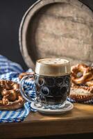 Oktoberfest oscuro cerveza con galleta salada de madera barril y azul Manteles foto